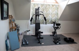 A compact home gym with essential fitness equipment like dumbbells, a yoga mat, and resistance bands in a cozy room.